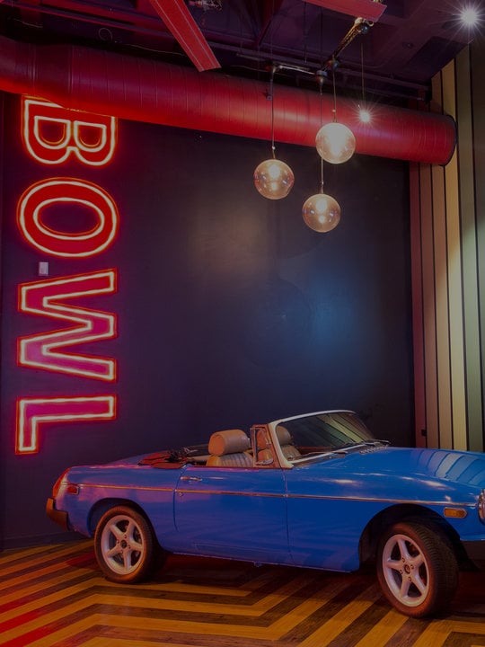 blue vintage convertible car next to neon BOWL sign